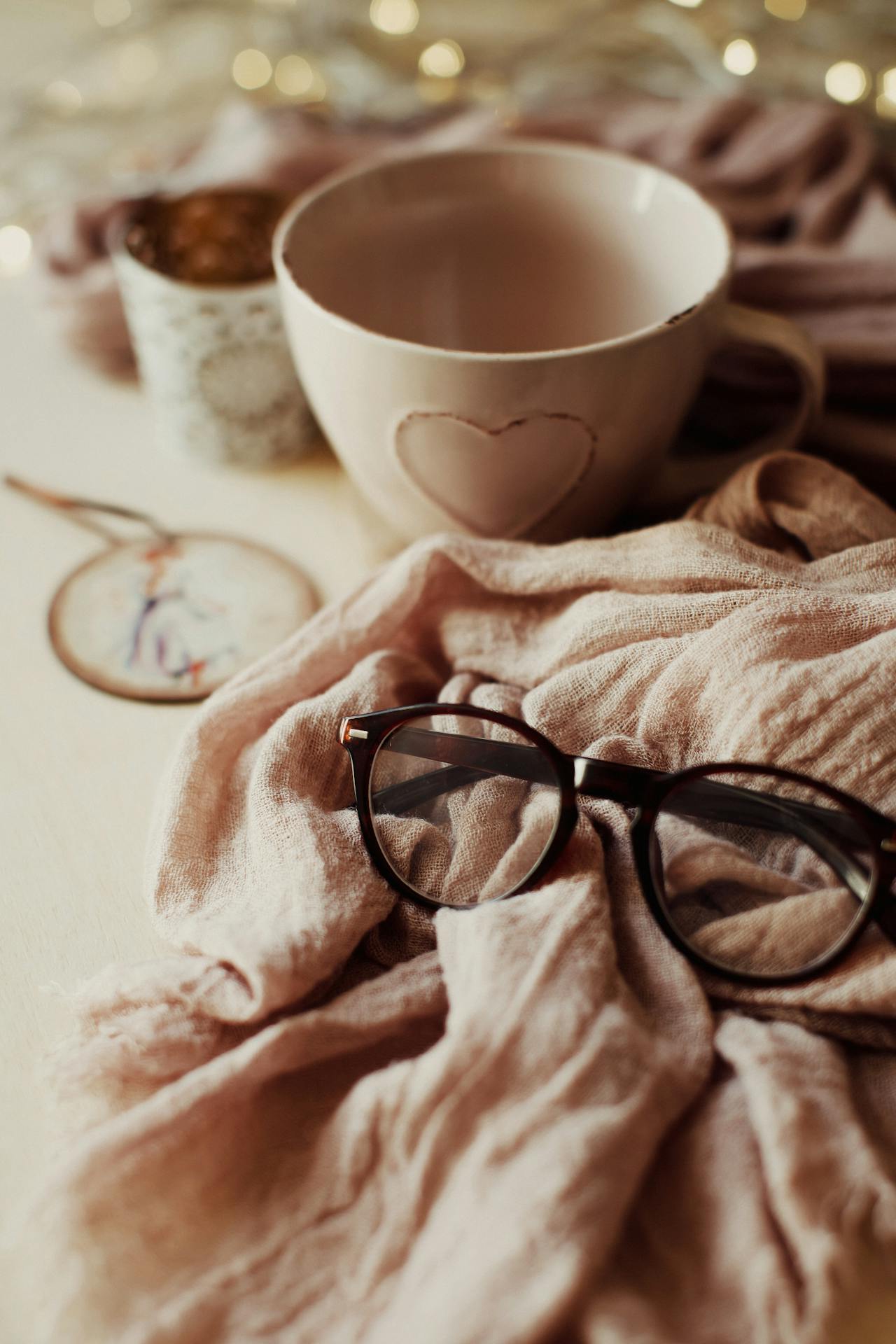 cozy scene of tea, eye glasses and blanket in netruals