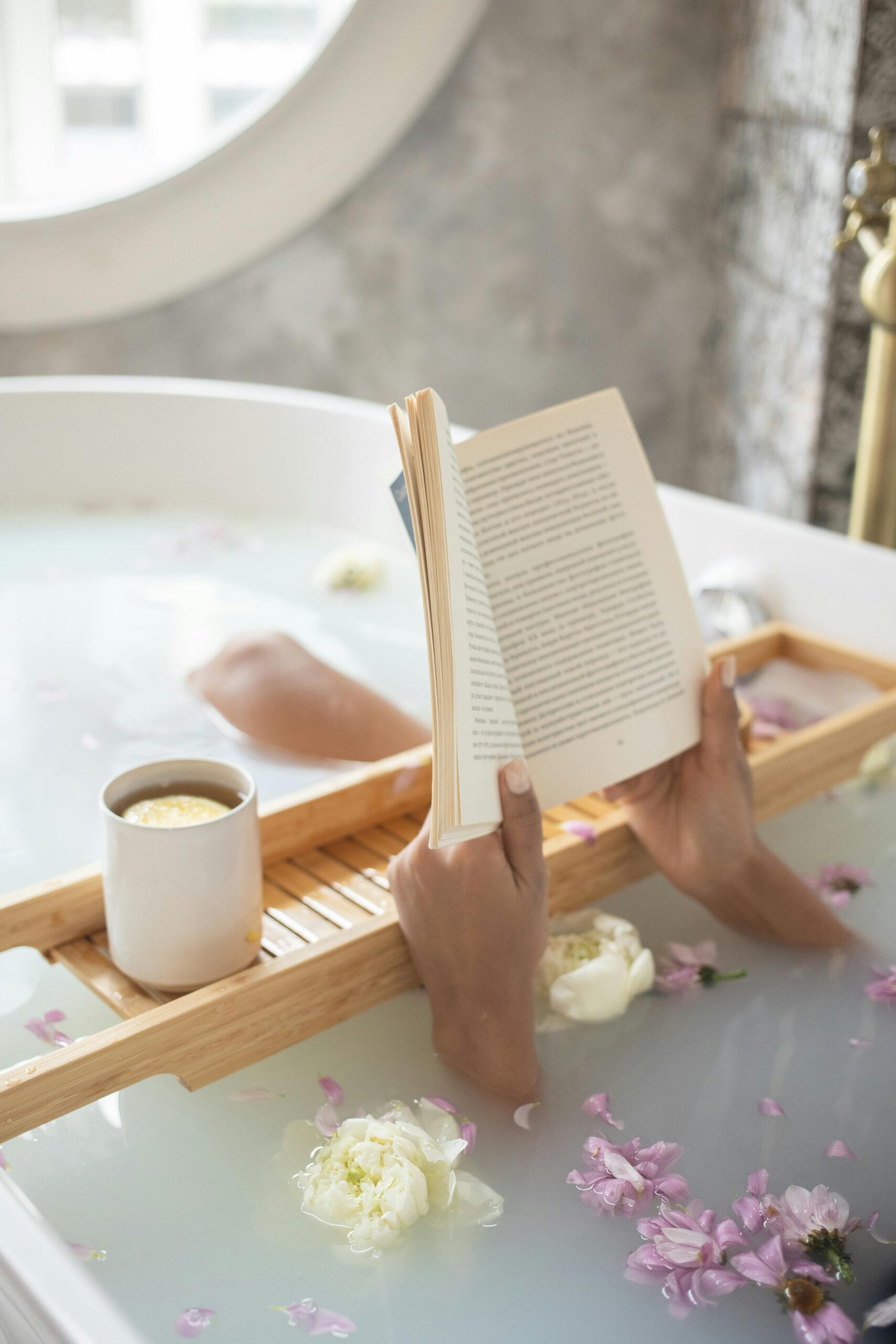 woman taking a bubble bath self care while reading a book